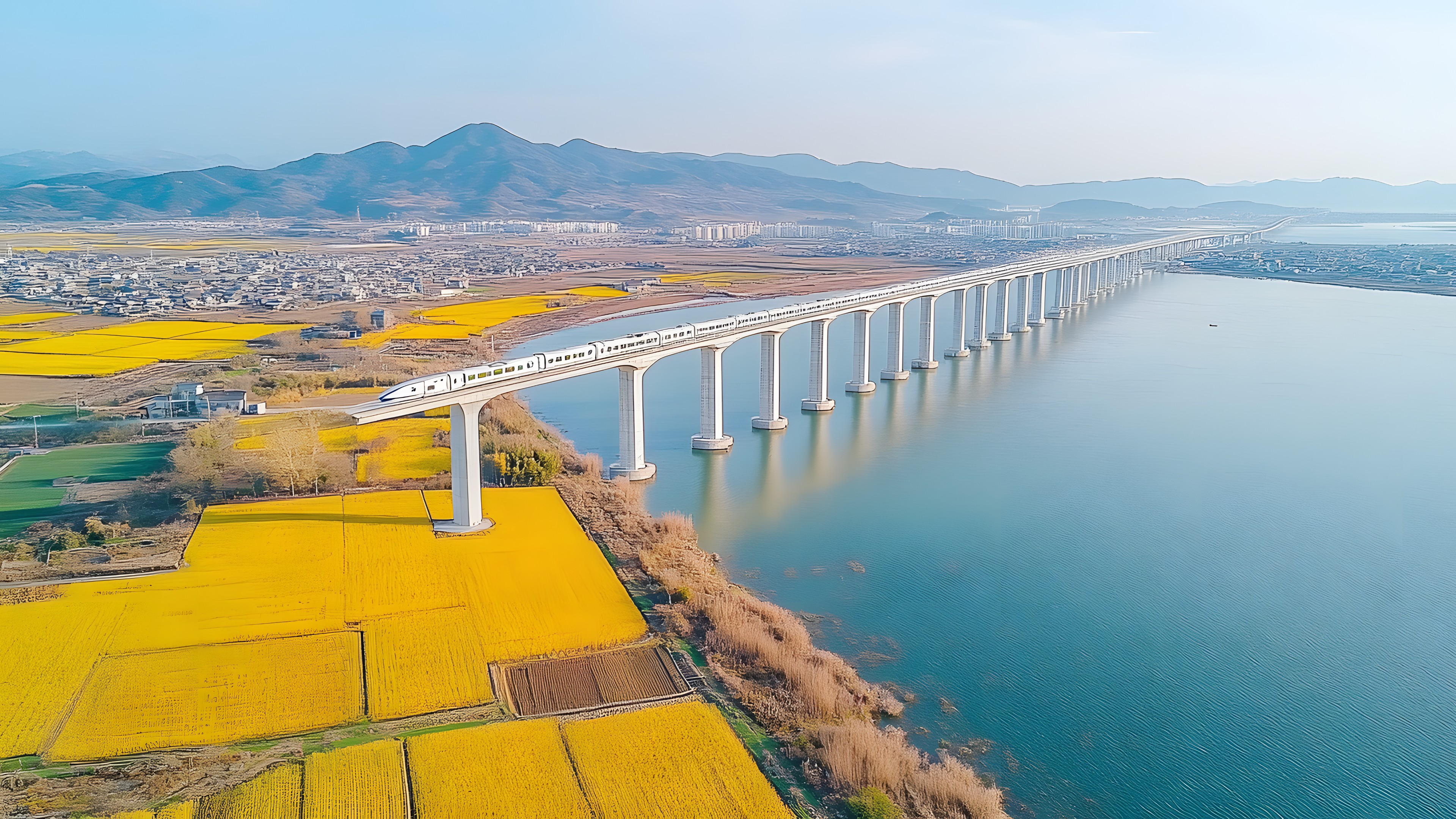 Water, Sky, Water resources, Azure, Mountain, Coastal and oceanic landforms, Lake, Bridge, Horizon, Landscape, Waterway, Headland, Road, City, Cloud, Suspension bridge, Concrete bridge, Reservoir, Cable-stayed bridge, Coast