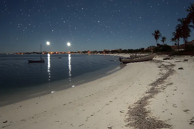 Sky, Body of water, Beach, Coast, Sea, Coastal and oceanic landforms, Shore, Sand, Ocean, Astronomical object, Watercraft, Dusk, Tropics, Evening, Palm trees, Caribbean, Boat, Shoal, Night, Bay